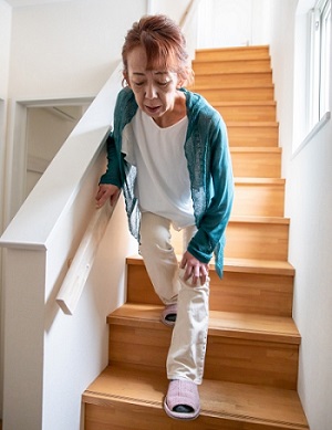 階段の上り下りで膝の痛み（変形性膝関節症）でつらい女性